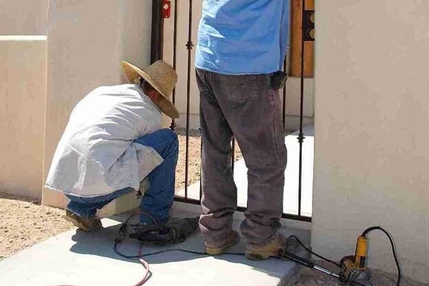 Technicians installing a new metal entry gate at a residential property