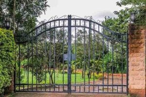 Black metal double swing gates installed at a residential driveway entrance