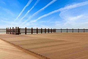 Large outdoor wood deck with railing overlooking an open landscape under a blue sky